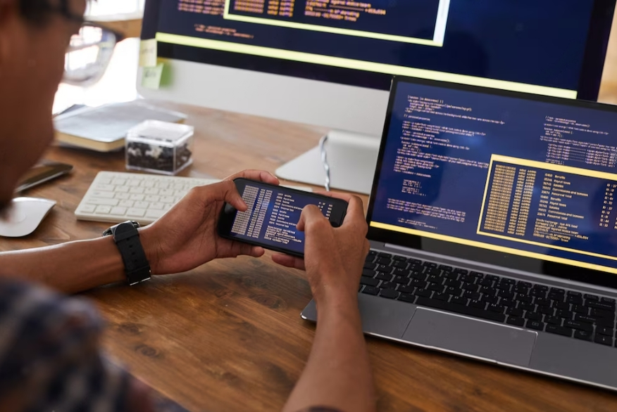 man holds smartphone with code on screen while working at desk in office