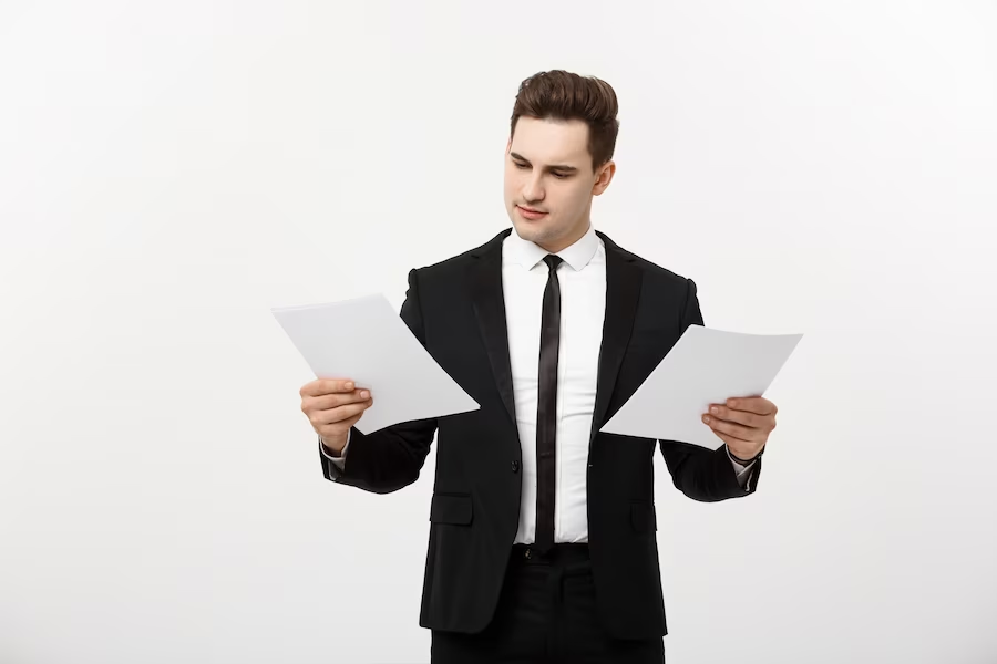 A man in a suit examining the documents he is holding